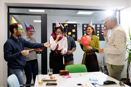 Business team celebrates birthday with cake and fun activities in modern office setting during afternoon hours