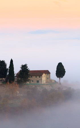 Chianti, November 2016: Tuscan landscape with country houses and cypresses in the autumn fog, on November 2016 in Chianti, Tuscany, Italyのeditorial素材