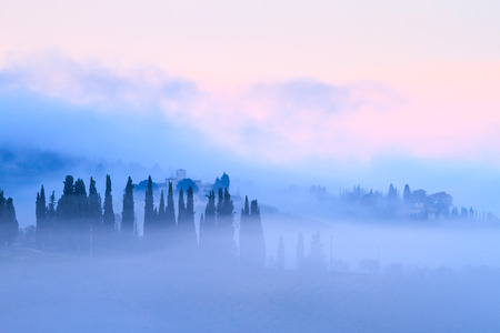 Tuscan landscape with country houses and cypresses in the autumn fog in Chianti, Tuscany, Italyの写真素材