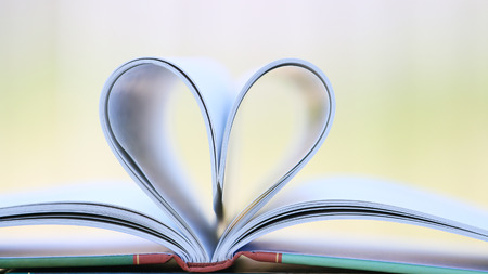 Book page in heart shape with green garden background