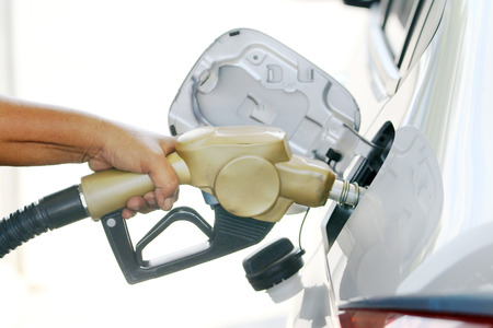 Fuel nozzle with hose, Closeup of woman pumping gasoline fuel in car at gas station.