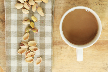 Pistachio nut and white coffee cup on wood background.の写真素材