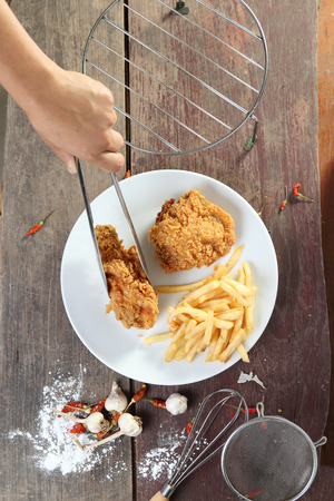 Woman Hand and fried chicken wings with french fries on wood table.の写真素材