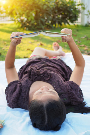 Asian woman reading book outdoor.の写真素材