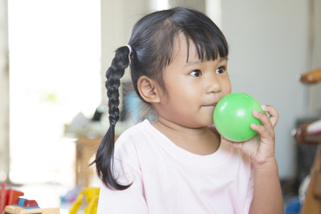 Asian little girl holding football and touch her mouse.の写真素材