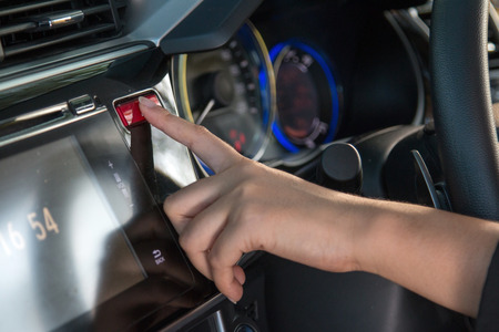 Business woman push emergency button in car, close up.