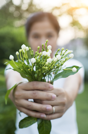 Asian woman hokding flowers in garden.の写真素材