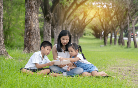 Asian family, mother, son and daughter doing reading activities at the park.の写真素材