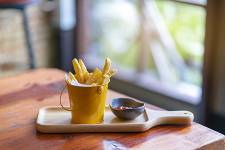 French fries and ketchup on wood board background.