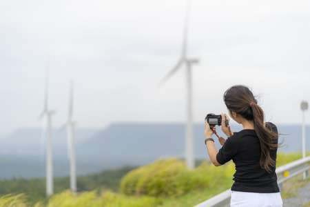 Asian women are very happy to photograph windmills and grasslands.の写真素材