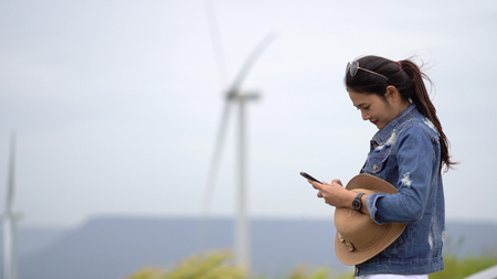 Asian women tourists are taking a picture of a wind turbine at a scenic spot.