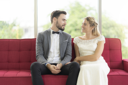 Couples sitting and talking happily at the red sofa, the newlywedsの写真素材