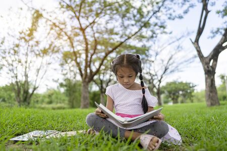 Asian girl is reading a book in the park.の写真素材