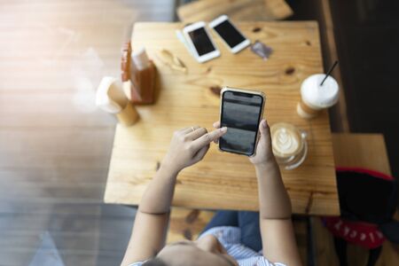 Asian woman using smart phone for  online shopping business in coffee shop cafe over blurred background.の写真素材