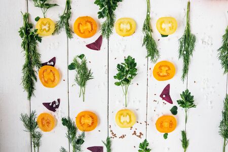 Colorful food ingredients pattern made of tomatoes, basil ,greens, dill and parsley on white...