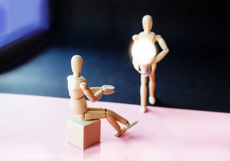 Two wooden little man, the first is sitting in anticipation of help, the second is going to meet with positive new ideas. oncept of support and mutual assistance between people.の写真素材