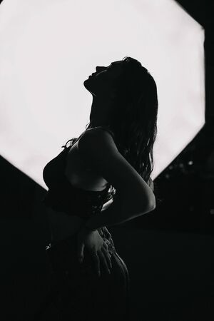 Silhouette of a beautiful lonely girl on a dark background in studio shot.の写真素材