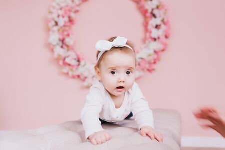 Image of sweet adorable baby girl with pink flowers, closeup portrait of cute 6 month-old smiling girl, beautiful toddler.の写真素材