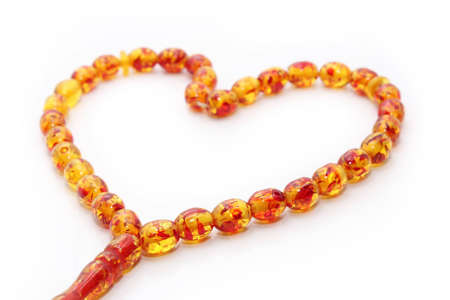 Amber beads in a heart-shaped closeup on a white background.の写真素材