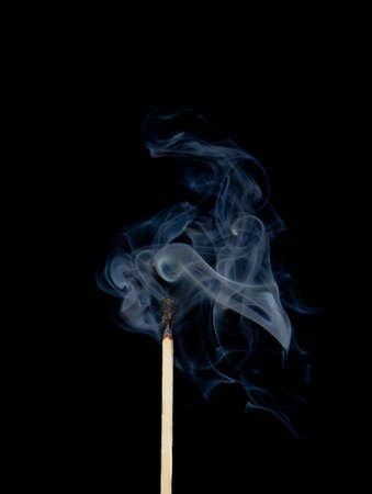 Burnt match in a smoke on a black background の写真素材