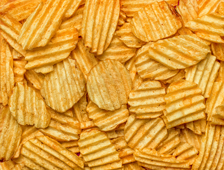 Background of potato chips close-up. The texture of the corrugated chips.