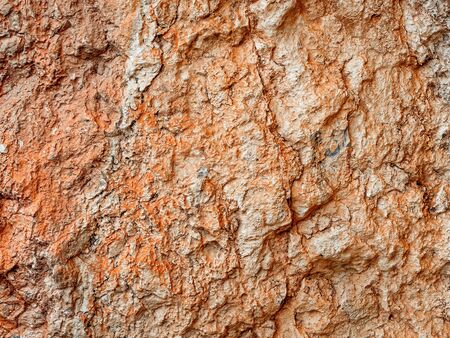 Rough texture of red stone with cracks and kinks close-up.