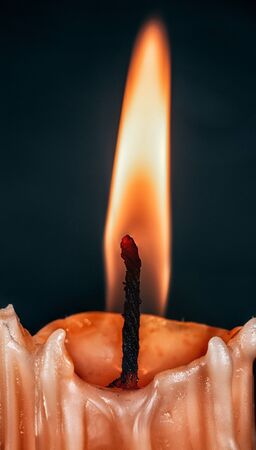 Burned candle with wax smudges close-up on a dark background.の写真素材