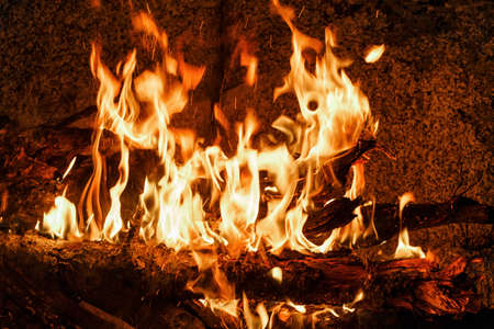 A bright flaming bonfire in front of a granite wall.の写真素材