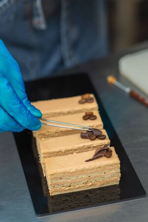 Hands of a confectioner with gloves make a chocolate cakeの写真素材