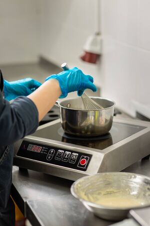 Gloved hands of confectioner make chocolate candiesの写真素材
