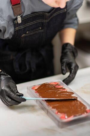 Gloved hands of confectioner make chocolate candiesの写真素材