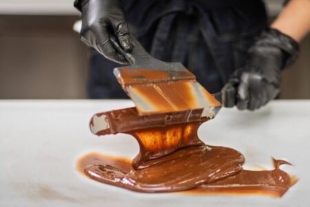 Gloved hands of confectioner make chocolate candiesの写真素材