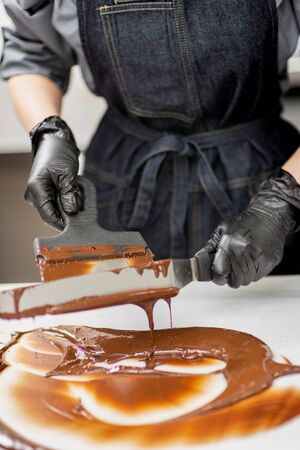 Gloved hands of confectioner make chocolate candiesの写真素材