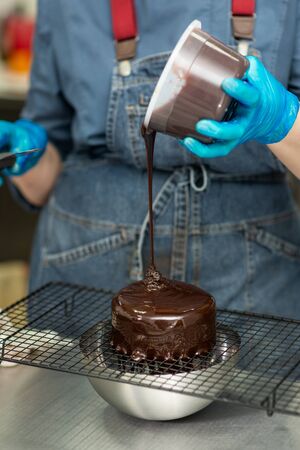 Confectioner makes chocolate cake with icing and creamの写真素材