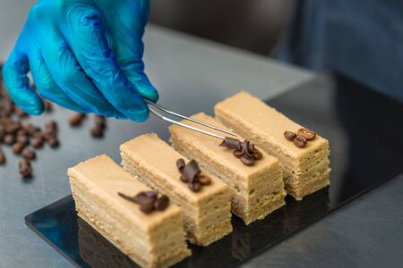 Hands of a confectioner with gloves make a chocolate cakeの写真素材