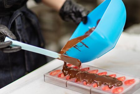 Gloved hands of confectioner make chocolate candiesの写真素材