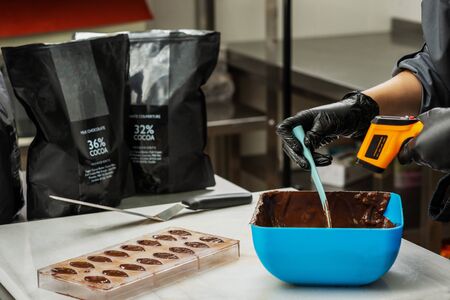 Gloved hands of confectioner make chocolate candiesの写真素材