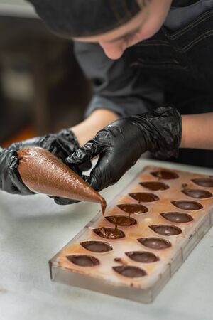 Gloved hands of confectioner make chocolate candiesの写真素材