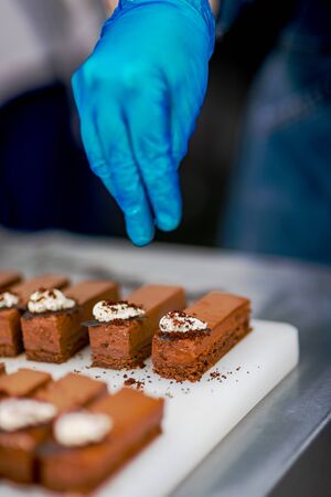 Hands of a confectioner with gloves make a chocolate cakeの写真素材