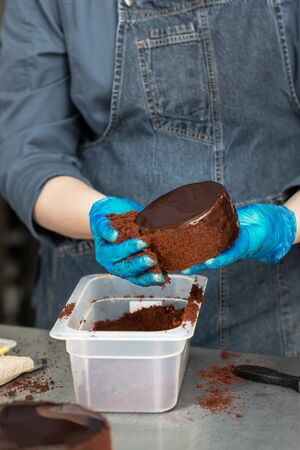 Hands of a confectioner with gloves make a chocolate cakeの写真素材