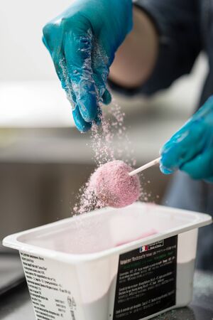 Gloved hands of confectioner make chocolate candies