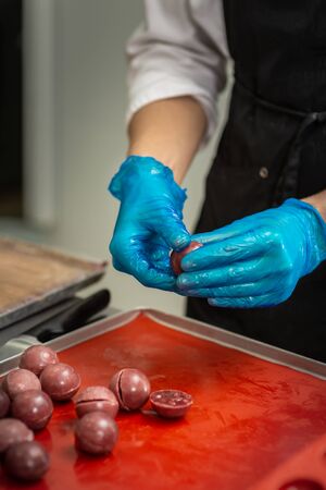 Gloved hands of confectioner make chocolate candiesの写真素材