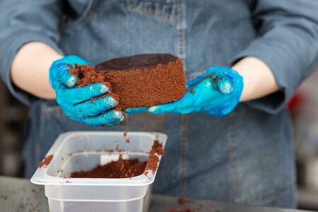 Hands of a confectioner with gloves make a chocolate cakeの写真素材