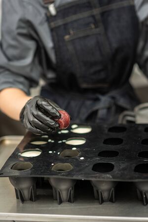 Gloved hands of confectioner make chocolate candiesの写真素材