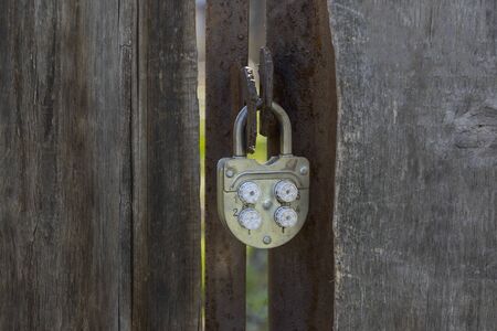 An old padlock code lock hanging on a wooden gate. Close-up.の写真素材