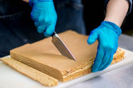 Hands of a confectioner with gloves make a chocolate cakeの写真素材