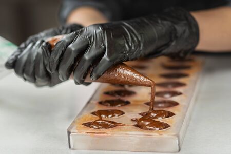 Gloved hands of confectioner make chocolate candiesの写真素材
