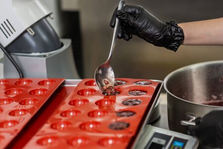 Gloved hands of confectioner make chocolate candiesの写真素材