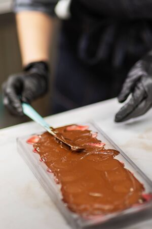 Gloved hands of confectioner make chocolate candiesの写真素材
