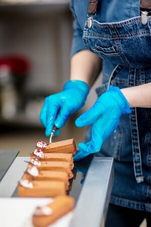 Hands of a confectioner with gloves make a chocolate cakeの写真素材